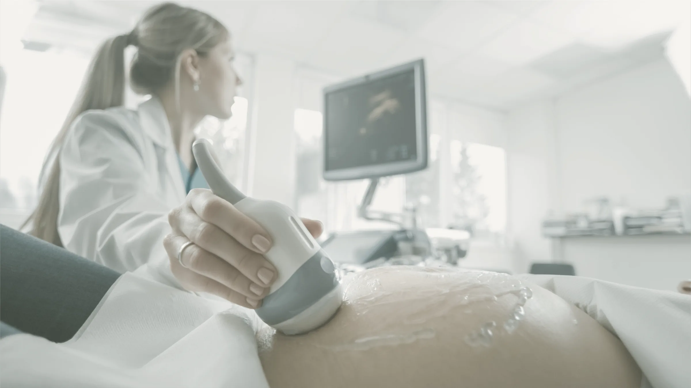A sonographer performing a pregnancy ultrasound in a calm, light-filled room